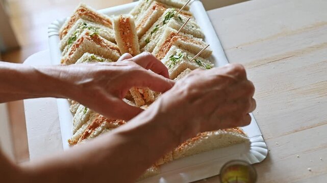 Close Up of Hands Adding Cocktail Picks to Mini Sandwiches, Food Finishing Touch, Appetizer Preparation, Catering Detail