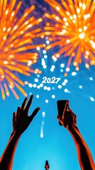 Obraz premium Hands capturing fireworks with smartphone under night sky with 2027 text