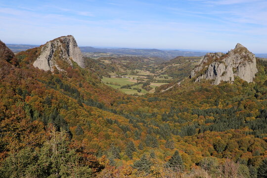 Aerial view of the Roches Tuiliere et Sanadoire volcanic peaks rising above a dense autumn forest in the Auvergne region, Orcival, Auvergne-Rhone-Alpes, France.