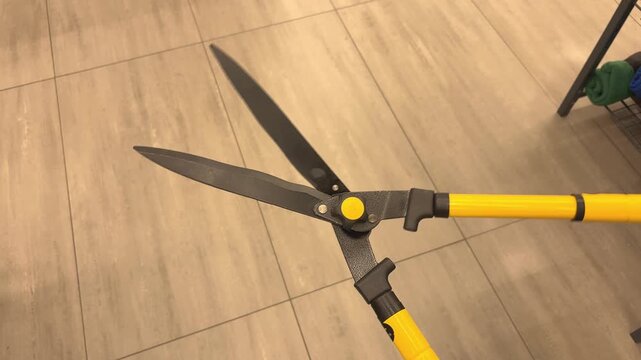 Close-up of yellow handled pruning shears for gardening and plant care, sharp cutting tool, horticulture and outdoor maintenance.
