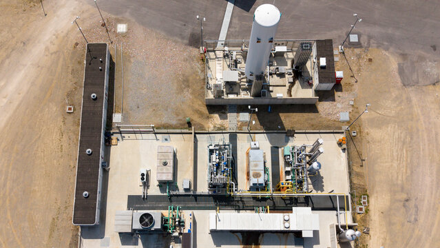 Aerial view of an LNG and CNG fueling facility with storage tanks, industrial piping, and concrete infrastructure in Lodi, Lombardy, Italy.