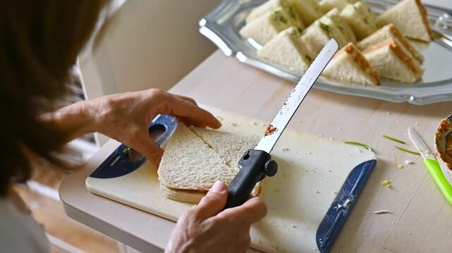 Woman Cutting Homemade Sandwich into Small Pieces on Kitchen Board to Prepare Mini Sandwiches, Recipe Preparation, Cooking Process, Food Tutorial, Party appetizers