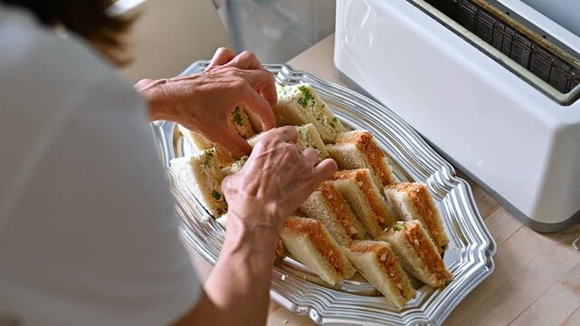 Woman Organizing Assorted Mini Sandwiches by Filling on Serving Tray, Food Preparation Workflow, Kitchen Organization, Appetizer Arrangement