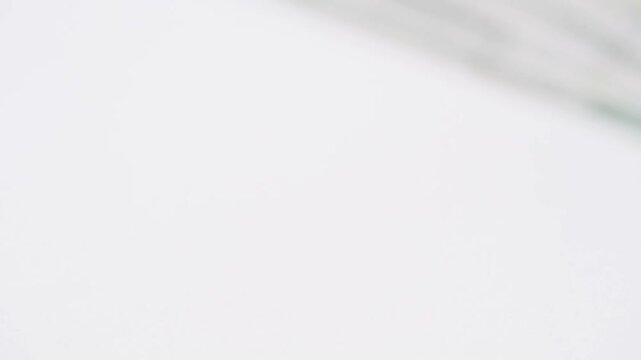 Out of focus hundred dollar bills drifting away across white surface, soft blur and shallow depth evoke fleeting wealth and uncertain finances, contemplative mood