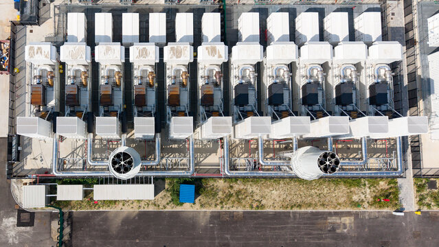 Aerial view of a row of industrial diesel backup generators at a data center facility with metallic piping and cooling systems in Milan, Lombardy, Italy.