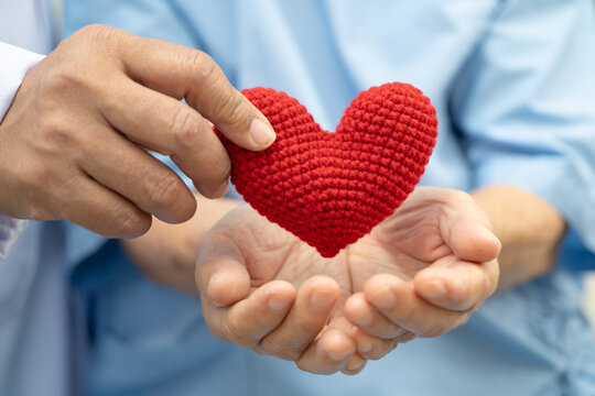 Doctor holding a red heart in hospital, healthy strong medical concept.