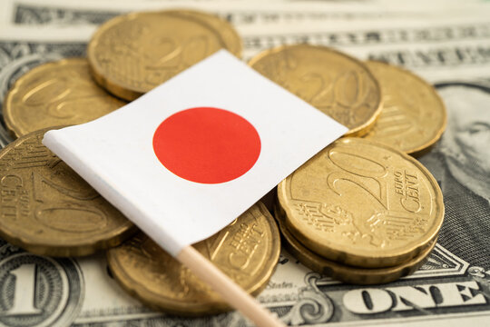 Stack of coins with Japan flag and US dollar banknotes.