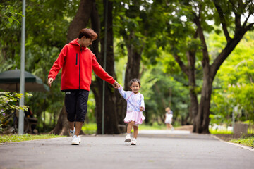 Fototapeta premium Energy, Asian girl and father running outdoor for child development or growth. Adventure, excited and path with happy kid in nature park for outdoors activity. Healthy outdoor sport for kids.