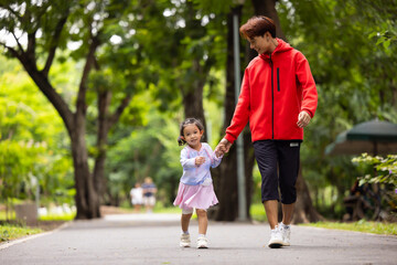 Fototapeta premium Energy, Asian girl and father running outdoor for child development or growth. Adventure, excited and path with happy kid in nature park for outdoors activity. Healthy outdoor sport for kids.