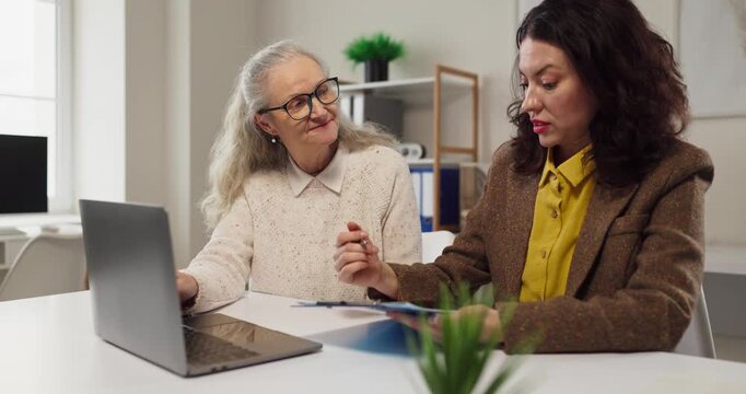 Senior woman and advisor discuss retirement planning. Consultation in an office with laptop and documents covers finance, savings and investments. Clear financial guidance for the client.