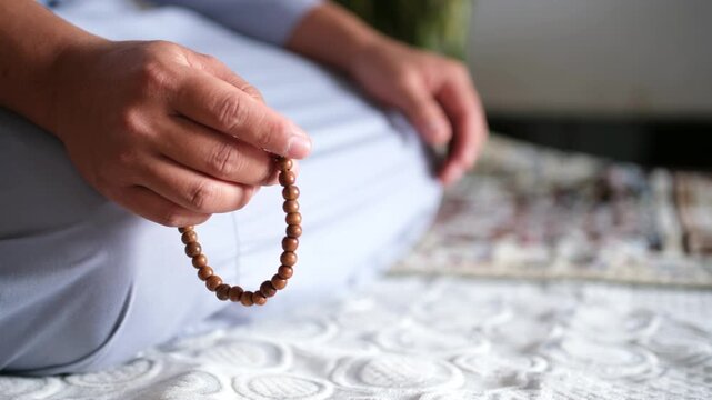 Close-up of hands reciting dhikr using prayer beads. Hands reciting dhikr. A man reciting dhikr while holding prayer beads. A Muslim's worship activity.
