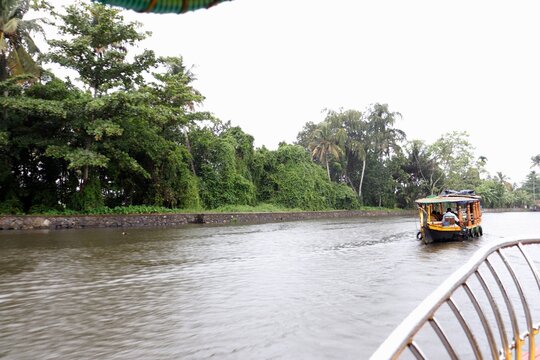 Ferry tour in a lake in Keralam, India on an overcast day, visiting coconut-tree islands.