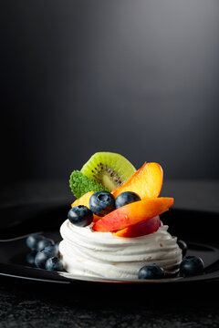 Pavlova dessert with nectarines, kiwis, blueberries, and mint.