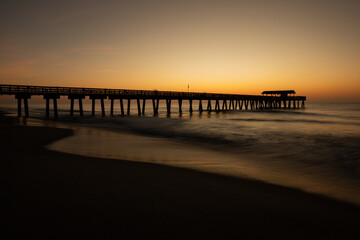 Fototapeta premium Tybee Island ocean fishing pier silhouette at golden sunrise, Georgia, USA.