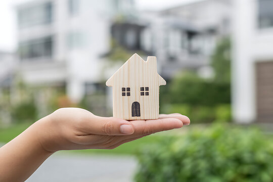 Small wooden house model in hand palm
