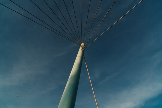 Low-angle view of a bridge pylon and radiating cables against blue sky