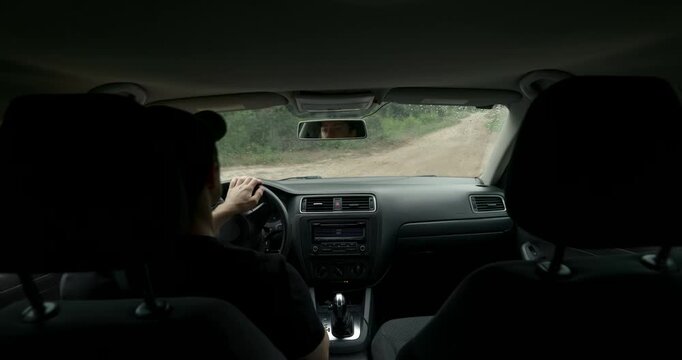 Back seat view of man driving car on road trip in rainy weather with audio included