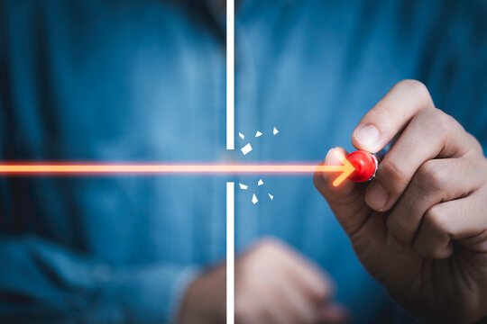 Business breakthrough and overcoming barriers concept with a hand pushing a glowing arrow through an obstacle for innovation, determination, problem solving, progress, success, leadership and growth.