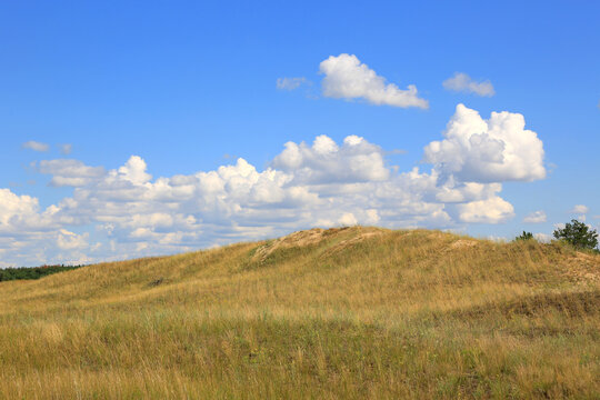 Beautiful summer landscape with rolling hills and fluffy clouds in the blue sky