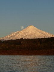 Villarrica volcano with moon over lake reflecting golden light © monica
