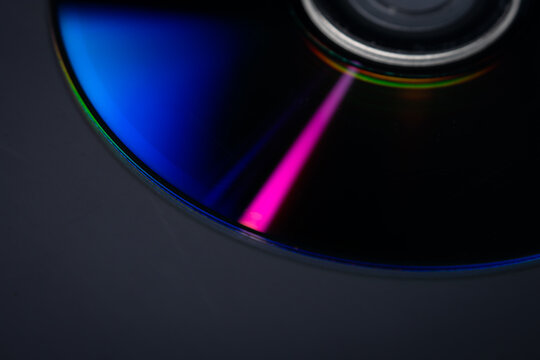Close up of a compact disc displaying vivid rainbow light reflections across its reflective surface. Concept data storage, digital media, optical technology, nostalgia, background and spectrum.