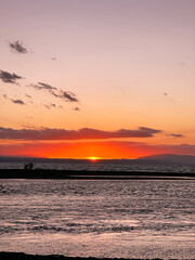 Vibrant sunset illuminating tranquil lake water and distant mountains © monica