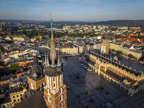 Aerial view of St. Mary's Basilica and the historic Main Market Square with its iconic Cloth Hall, surrounded by traditional rooftops and urban architecture in Krakow, Malopolska, Poland.