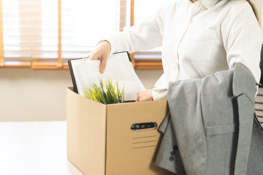 Unemployed, quite job. Desperate asian young businesswoman resigning from company, hand holding cardboard, packing belongings, stuff into box, layoff or changing work. Resignation, employment concept.