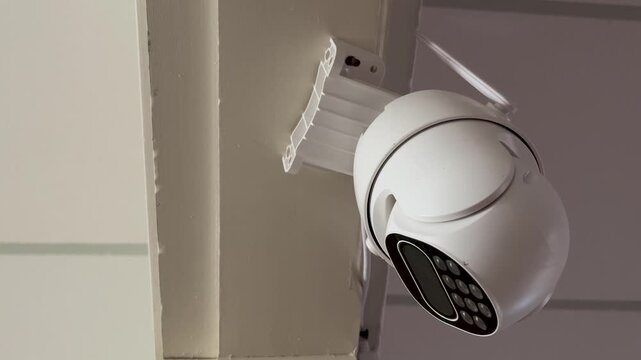 Modern white robotic security camera with pan-tilt-zoom functionality remotely monitoring and scanning an indoor area.