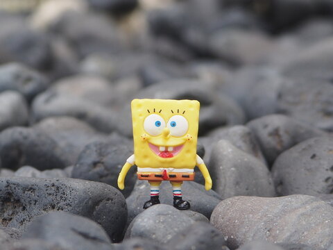 Indonesia - May 18, 2025 : Mini toy of action figure at outdoor with blurred background. Miniature photography concept design. Minifigure of Spongebob Squarepants character from cartoon film.