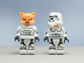 Fototapeta premium Indonesia - May 16, 2025 : Mini toy of action figure at table with blurred background. Miniature photography concept design. Minifigure of Stormtrooper character with orange cat. Surprise moment.