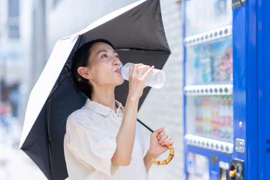 自販機で飲み物を買う女性