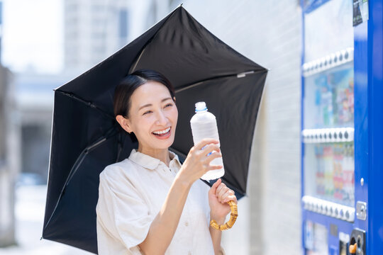 自販機で飲み物を買う女性