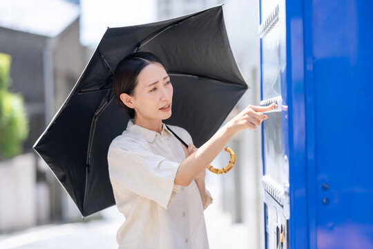 自販機で飲み物を買う女性