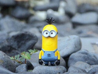 Naklejka premium Indonesia - May 18, 2025 : Mini toy of action figure at outdoor with blurred background. Miniature photography concept design. Minifigure of Minions character from Despicable Me animation film.