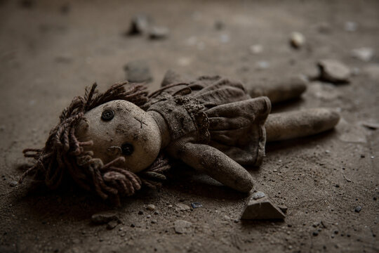 A soiled cloth doll lying on the ground, showing signs of wear.