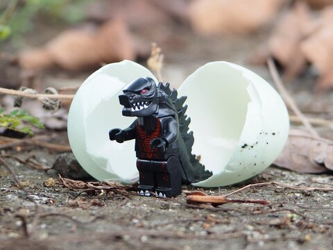 Indonesia - May 3, 2025 : Mini toy of action figure at outdoor with blurred background. Wild photography concept design. Minifigure of Baby Godzilla character coming out from egg. New born concept