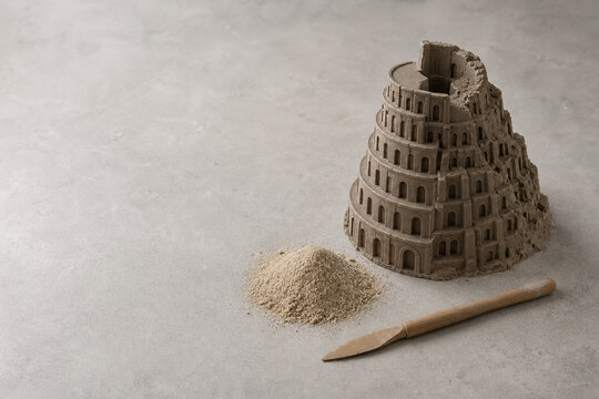 Half-formed clay Tower of Babel model with sand and tool, communication and learning concept