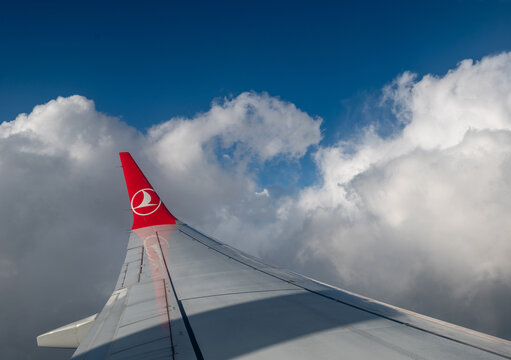 Caselle airport, turin province, italy. August 1, 2025. Turkish airlines aircraft wing flying over caselle airport, turin, italy. Experiencing travel, aviation, and clear blue sky with white clouds