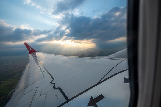 Caselle airport, turin province, italy. August 1, 2025. Airplane wing and cloudscape with sun rays from a turkish airlines flight over caselle airport, turin, italy. Travel concept