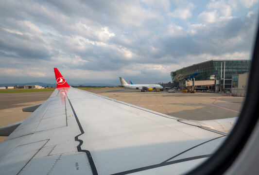 Caselle airport, turin province, italy. August 1, 2025. Airplane wing and tailfin of a turkish airlines plane parked on the tarmac at caselle airport, turin, italy, under a cloudy sky