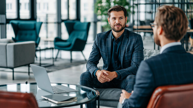 Faceless professionals in consultation viewed from over the shoulder in a modern bright workspace with laptop notebook and natural light