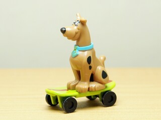 Fototapeta premium Indonesia - February 10, 2026 : Mini toy of action figure at outdoor with blur background. Miniature photography concept design. Minifigure of Scooby character playing skate board at sport arena.