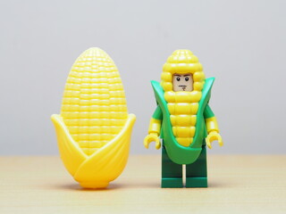 Fototapeta premium Indonesia - February 10, 2026 : Mini toy of action figure at outdoor with blur background. Miniature photography concept design. Minifigure of corn guy character with corn cob at garden.