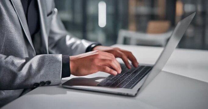 Business professional typing on a laptop computer in modern office setting