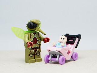 Fototapeta premium Indonesia - December 10, 2025 : Mini toy of action figure at outdoor with blurred background. Miniature photography concept design. Minifigure of Mosquito and baby character with stroller at outdoor.