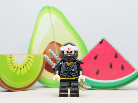 Indonesia - December 5, 2025 : Mini toy of action figure at outdoor with blurred background. Miniature photography concept design. Minifigure of Ninja Go character with Avocado, Water Melon and Kiwi.