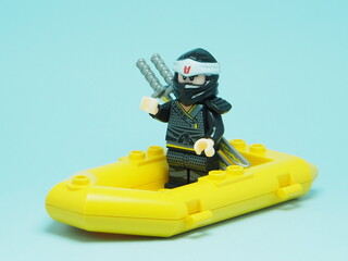 Fototapeta premium Indonesia - December 4, 2025 : Mini toy of action figure at outdoor with blurred background. Miniature photography concept design. Minifigure of Ninja Go character sailing with rubber boat at ocean.