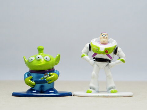 Indonesia - November 27, 2025 : Mini toy of action figure at table with blur background. Miniature photography concept design. Minifigure of Woody, Buzz Lightyear and Green Alien character from film.