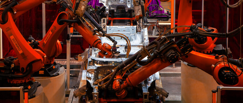 Robotic arms are working on the car production line at the car factory.